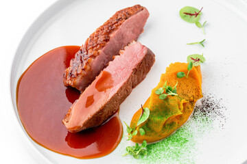 Grilled fillet beef steak or grilled beef medallion with vegetable puree and sauce in plate isolated on white background. Meat dishes, top view, close up