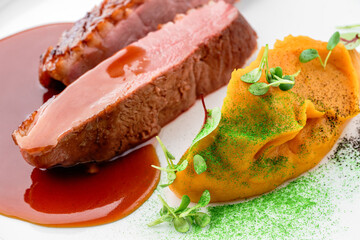 Grilled fillet beef steak or grilled beef medallion with vegetable puree and sauce in plate isolated on white background. Meat dishes, top view, close up