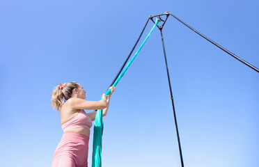 Acrobat woman checks the hold of the fabrics and structure to safely practice aerial dance