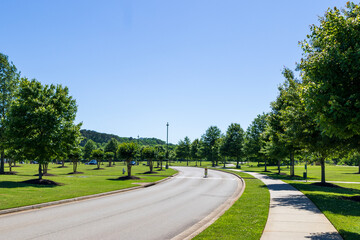 Fototapeta premium A long winding road in a gorgeous landscape at Etowah River Park with lush green trees and grass in Canton Georgia USA