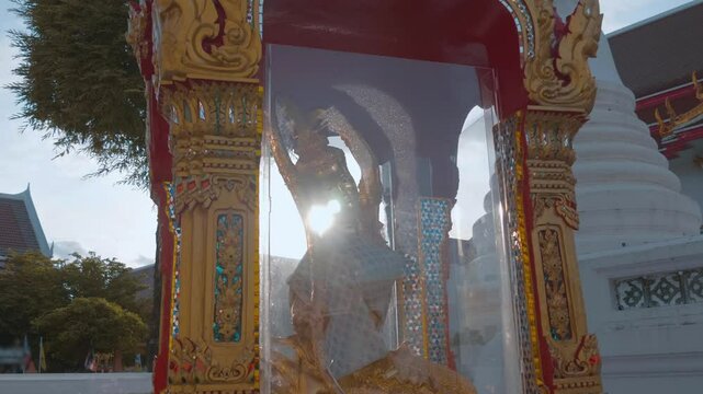 An amazing golden statue of Phra Mae Thorani Bip Muai Hpom - Mother Earth stands in the temple grounds of Wat Chana Songkhram in Bangkok, Thailand. Shot in motion. Closeup