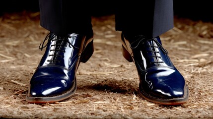 Close-up of shiny black leather dress shoes worn by a person standing on dirt ground
