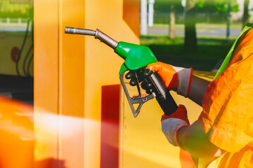 Gas station worker in signal clothing holding a gasoline gun at a fueling station. Fueling station...