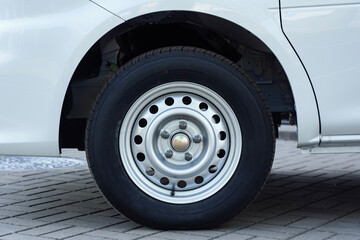 White van wheel with a steel rim, parked on a paved surface.