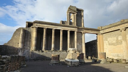 Pompeii, Italy - 8 January 2025. Wide view of Pompeii&rsquo;s Basilica showing the colonnaded tribunal platform, partially standing upper structure, and parts of brick and stone columns in the foreground.