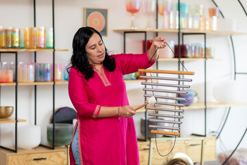 Woman playing bar chimes in a sound healing studio with tibetan singing bowls