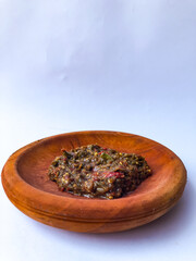 Terasi chili sauce or shrimp paste that is ground with a pestle or a traditional tool that Indonesians usually use to grind herbs and spices, terasi chili sauce in a pestle with a white background