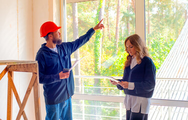 architect-designer and foreman-engineer at a construction unfinished renovated site discuss inspect...