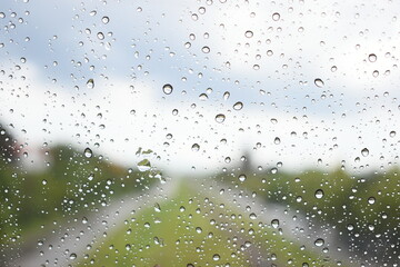 water drop on mirror with blue sky and green grass road