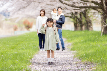 桜の咲く公園を歩く家族