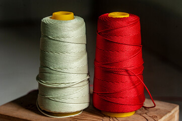 Close-Up of Spools of White and Red Thread on a Wooden Surface