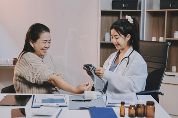 Doctor using sphygmomanometer with stethoscope checking blood pressure to a patient in the hospital.