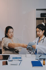 Fototapeta premium Doctor using sphygmomanometer with stethoscope checking blood pressure to a patient in the hospital.