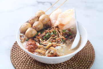 a bowl of chicken porridge with quail eggs satay, warm food