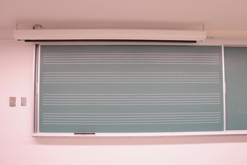 A chalkboard at the wall for music education. A green school board with horizontal lines.