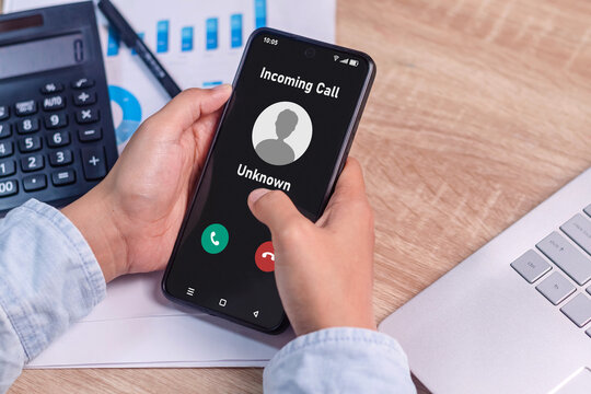 Woman's hand holding a smartphone with an incoming call from an unknown number on the screen. Spammer incoming call concept.