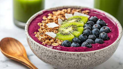 Colorful Smoothie Bowl with Fresh Fruits, Granola, and Coconut Flakes on Marble Background with Green Drinks in Glasses