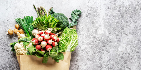 Healthy vegan eating, cooking, shopping. Eco fiendly paper bag with fresh vegetables, herbs, mushrooms, asparagus, radish, broccoli from local farm market. Food background