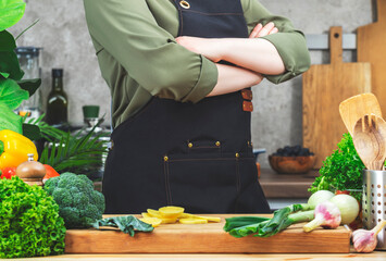 Chef confidently holds arms crossed over chest. Cooking food in the kitchen. with wooden table,...