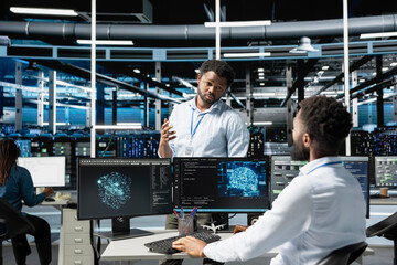 Data center manager supervising work done by engineer using deep learning algorithms to analyze datasets. Server farm team leader overseeing worker using AI tech to recognize data patterns