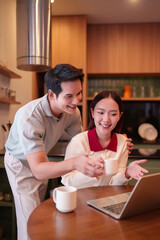 Happy Asian Couple Enjoying Coffee Break While Working on Laptop Together at Home Kitchen Modern Lifestyle Technology