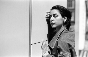 Young woman leaning against wall with closed eyes in monochrome analog photography