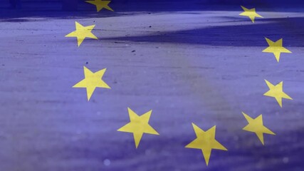 Low sunlight sparking EU stars drifting over concrete then woman striding carrying red shopping bag - Powered by Adobe