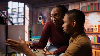 Coworkers looking at PC screen in startup office, managing cloud computing resources and platforms...