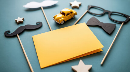 Father's Day Still Life with Yellow Card, Car, Mustache, Bow Tie, Glasses, and Star Decorations on Blue Surface