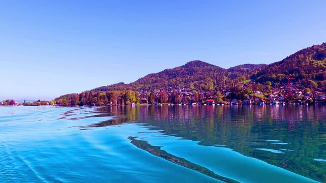 Travel along Thun lake in Switzerland on boat view with calm water wave n green mountain, 4k magenta clear blue sky over colorful traditional house n hill village in sunny spring or summer sunlight 