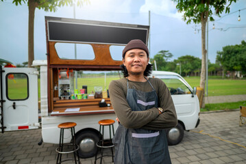 Indonesian southeast asian male barista standing with confidence in front of his coffee shop. A small business of a coffee shop or cafe on a truck
