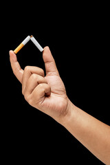 Human hand breaks a cigarette, rolled tobacco in paper with a filter tube, with a black background....