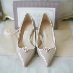 Elegant bridal footwear detail, beige heels with pearl embellishments closeup