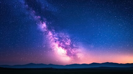 Naklejka premium Vibrant milky way arching across a deep blue night sky over a tranquil landscape, creating a breathtaking celestial view