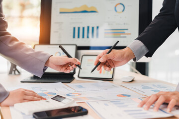 Business dashboard analysis with charts and graphs on paper and digital screens, two people discussing data and strategy in modern office environment with teamwork and focus
