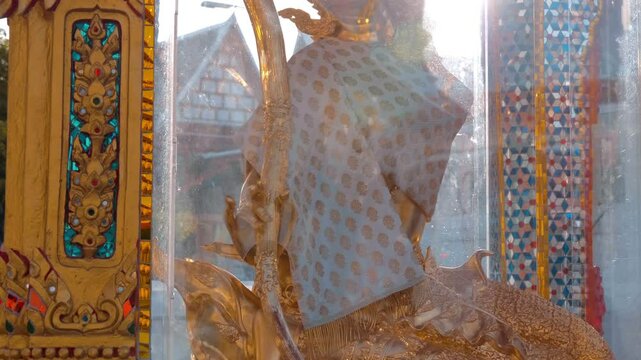 An amazing golden statue of Phra Mae Thorani Bip Muai Hpom - Mother Earth stands in the temple grounds of Wat Chana Songkhram in Bangkok, Thailand. Shot in motion. Closeup