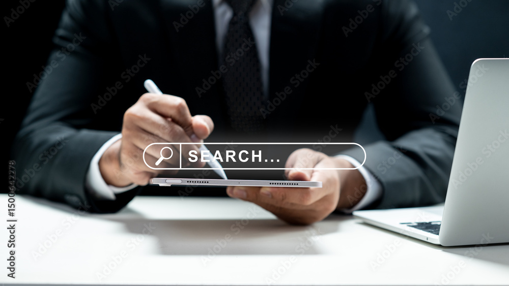 Poster businessman using a tablet and showing a search engine bar icon on the screen. laptop on the desk. t
