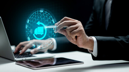 Businessman using a laptop and showing a cargo truck icon on the tablet screen. Laptop on the desk. Technology innovation on the virtual screen. Concept of industry, transport, and logistics