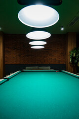 Gathering spot features a vibrant green billiard table illuminated by stylish overhead lights