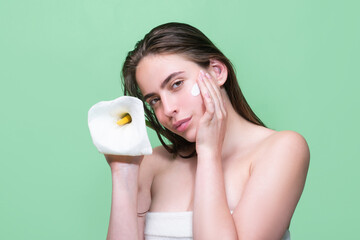 Beauty portrait of a beautiful half naked woman applying face cream isolated on studio background....