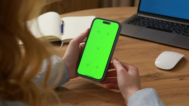 Woman sit use digital tech cell phone open green screen mock up. Hand scroll phone web site swipe unlock. Girl hold mobile closeup. Turn on chroma key page Cozy home background. Online app copy space