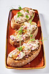 Savory tuna salad spread generously on toasted bread, elegantly garnished with fresh microgreens