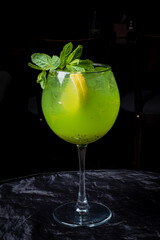 A refreshing cocktail blends vivid green hues with mint and lemon, served in a stylish glass