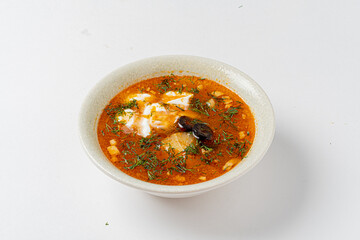 A vibrant bowl of spicy fish stew, adorned with fresh herbs, invites hearty culinary exploration