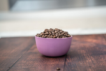 Organic natural coffee beans in a pink bowl