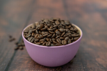 Organic natural coffee beans in a pink bowl