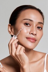 Fototapeta premium Close-up of woman applying serum to face