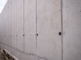 Smooth concrete wall with visible joints and embedded fasteners, captured in an urban environment with minimalistic and industrial feel.
