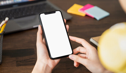 Hand holding smartphone with a blank screen on table, for putting advertising to promote.