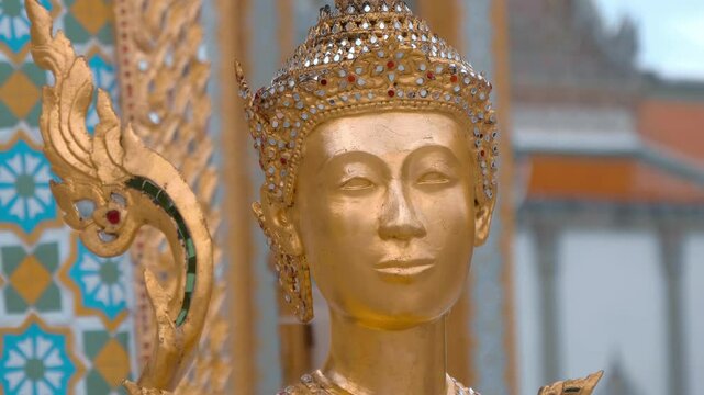 Masterfully crafted graceful exotic mythical creature Golden Kinnaree (Kinnari, Kinari) statue stands in Grand Palace in Bangkok. Shot in motion. Closeup